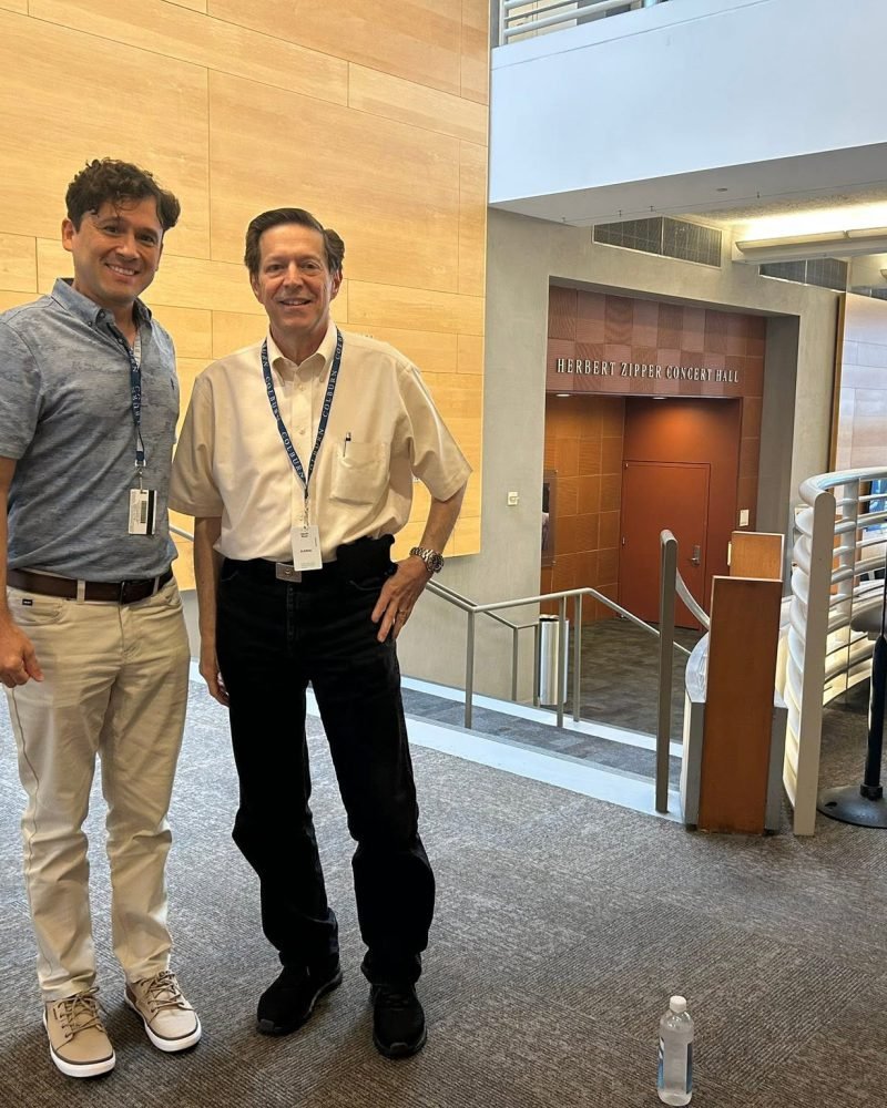 Carlos Boza standing beside a colleague in the lobby of the Colburn School, outside the Herbert Zipper Concert Hall