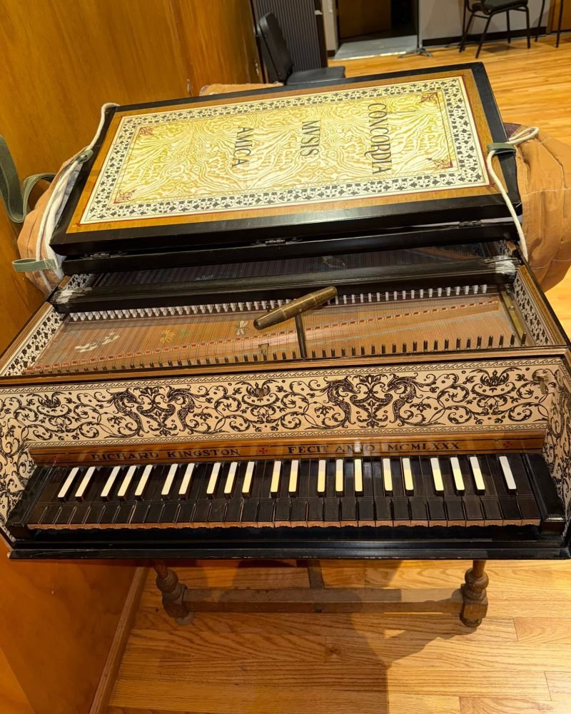 Two-manual harpsichord with an ornately decorated case and a painted lid, seen from the keyboard end