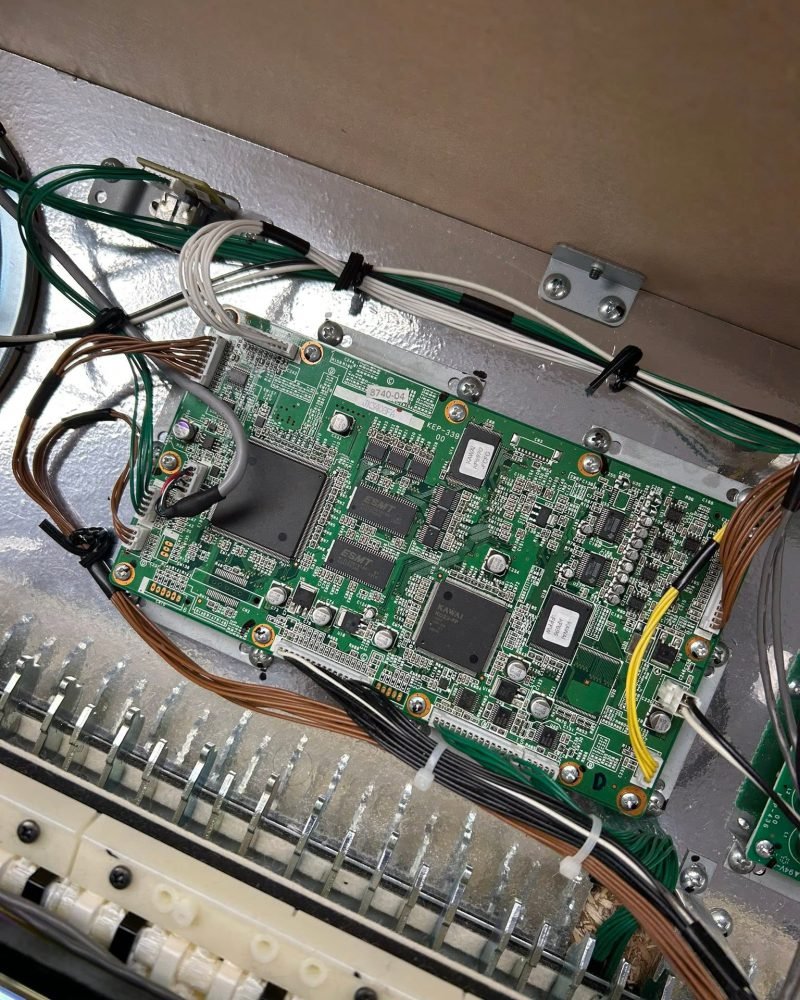 Green circuit board and wiring inside a Kawai digital piano, above the row of key sensors