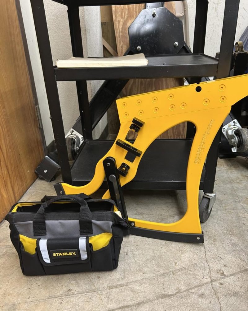 Yellow piano lifting tool and a tool bag on a workshop floor